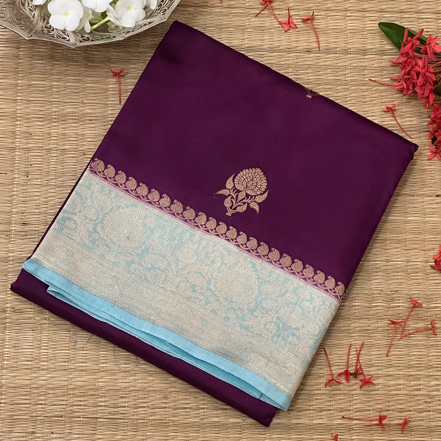 Plum and blue saree with floral design on a woven surface